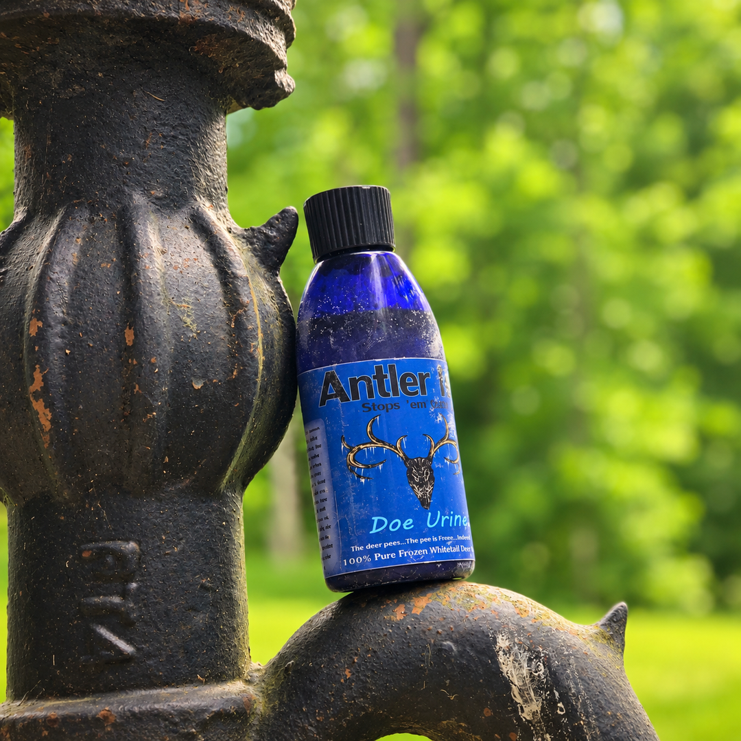 A blue bottle of Antler Ice's 'Doe Urine' placed on a dark metal garden stake with a blurred green garden background.