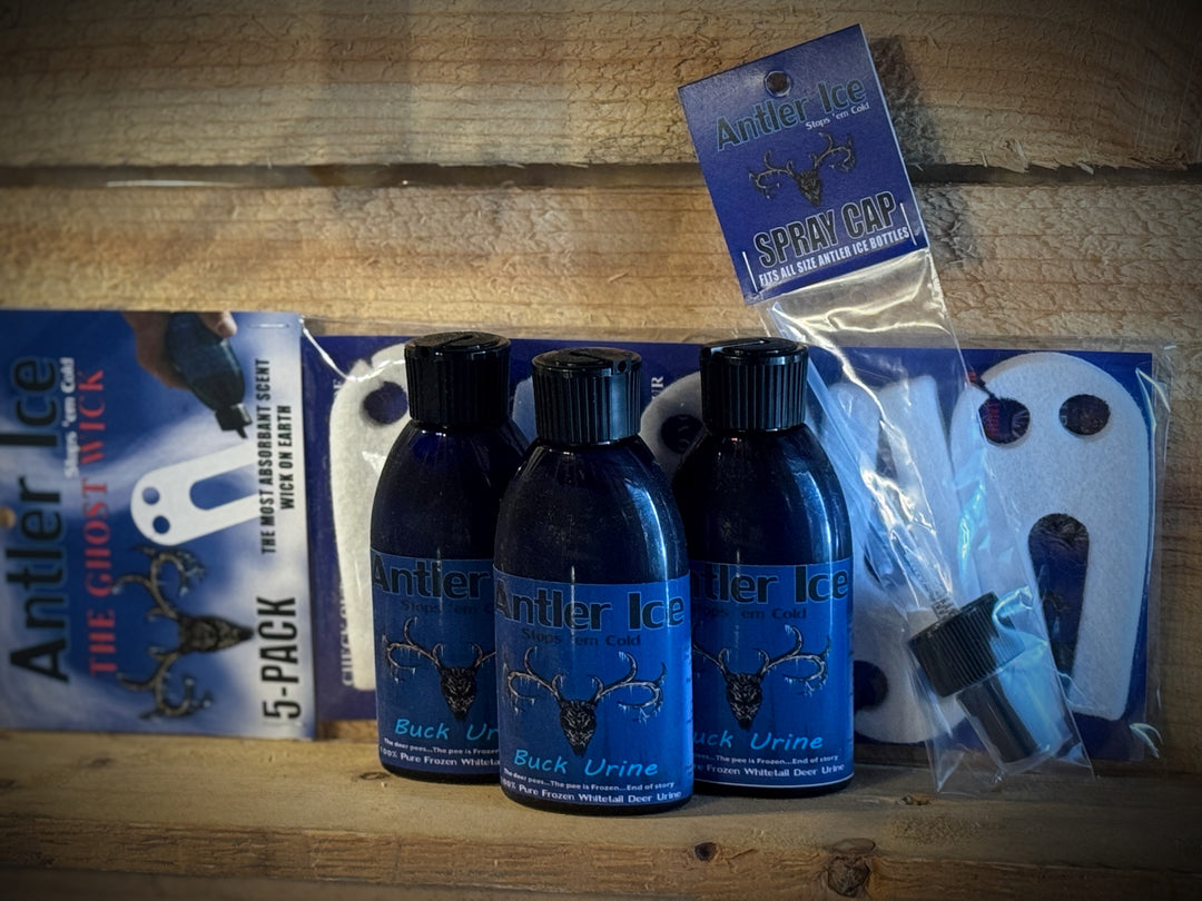 Three bottles of Antler Ice buck urine on a wooden surface with packaging and labels, including a spray top and a 5 pack of Ghost Wicks
