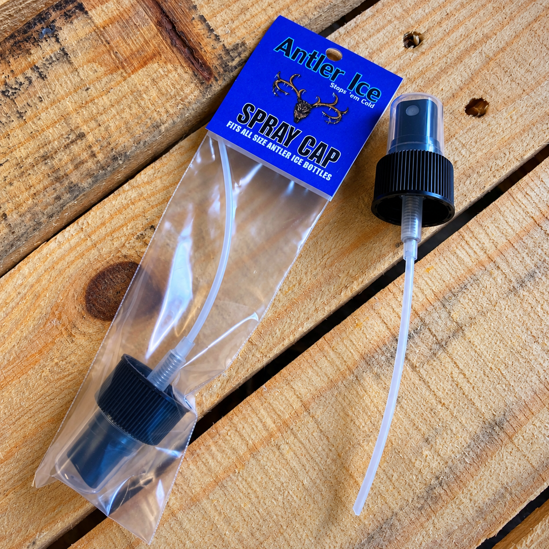 A clear plastic spray cap package with a blue header card reading 'Antler Ice SPRAY CAP' and a black spray cap with a clear tube, placed on a wooden surface.