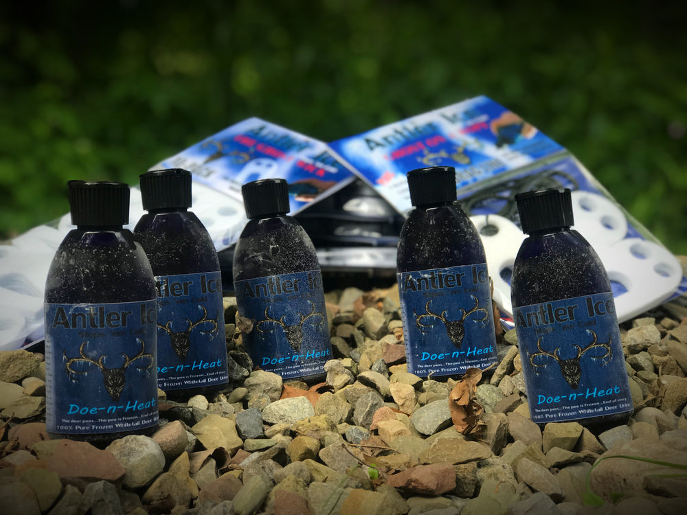 Several bottles of Doe-n-Heat wildlife attractant laid out on rocks with Ghost Wick packaging visible in the background.